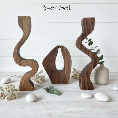Skulpturale Kerzenhalter aus massivem Nussbaum in drei Designs. Einzeln oder als 3er-Set – moderne Tischdeko für Stabkerzen Ø 20–22 mm.